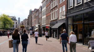 Een gezellige winkelstraat in stad met mensen die langs verschillende winkels wandelen op een zonnige dag.